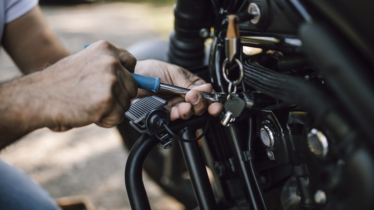 Le mani di un meccanico al lavoro sul motore di una moto con un cacciavite